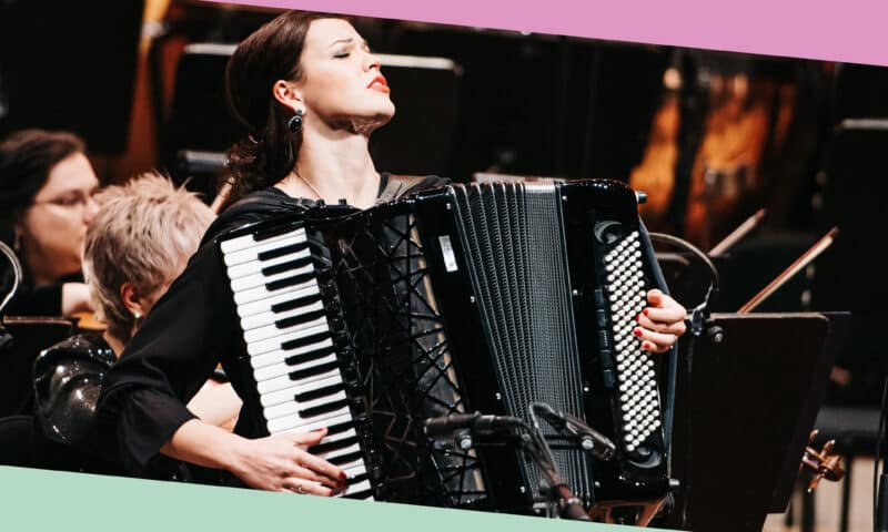 Accordionist Ksenija Sidorova in performance, with orchestra behind her